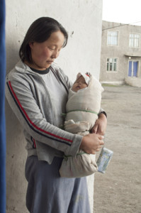 姿勢が良くなるように布と紐で固定されたモンゴルの赤ちゃん